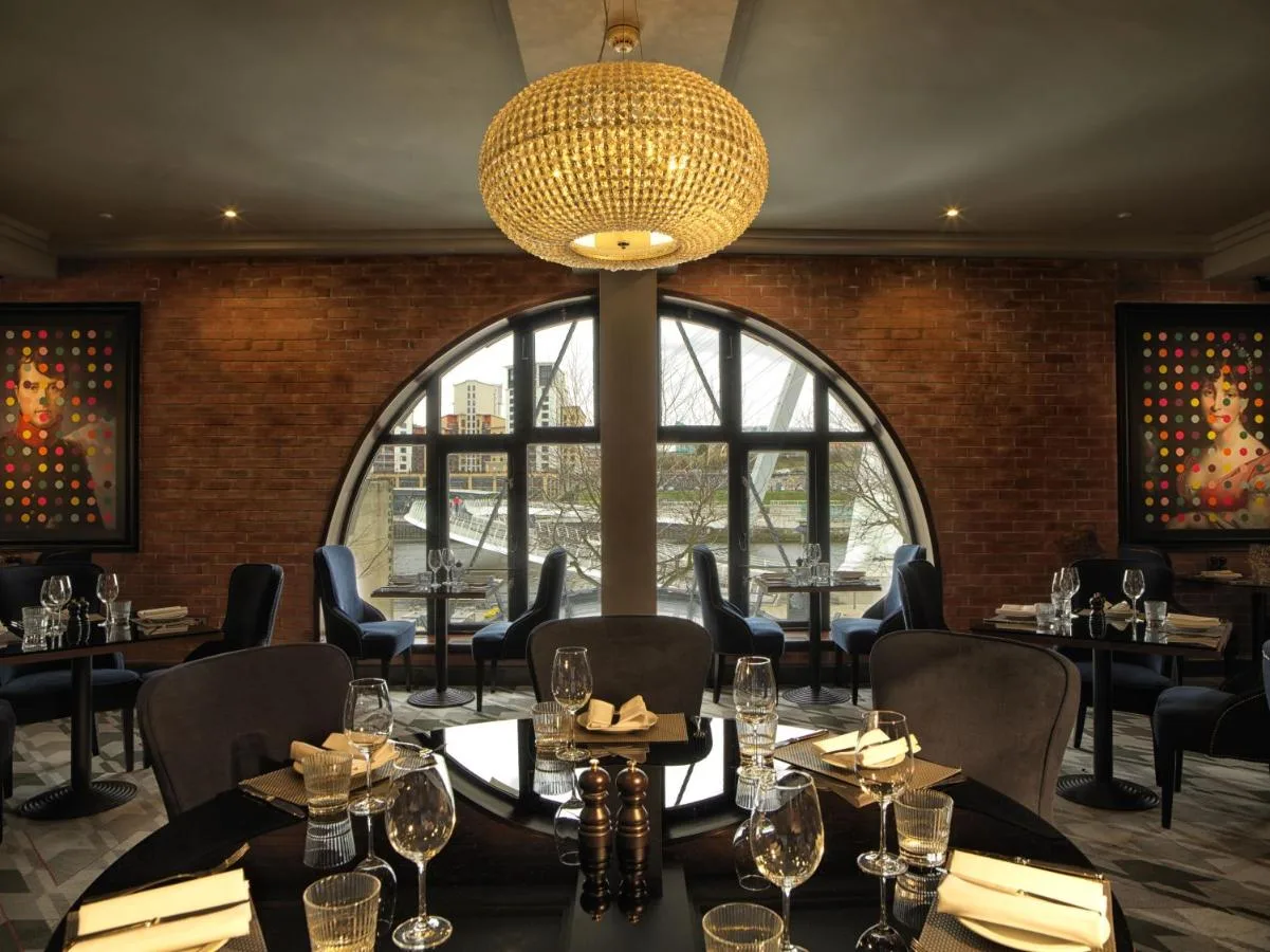 A dining room with tables and chairs and a large window at Malmaison Newcastle in Newcastle upon Tyne