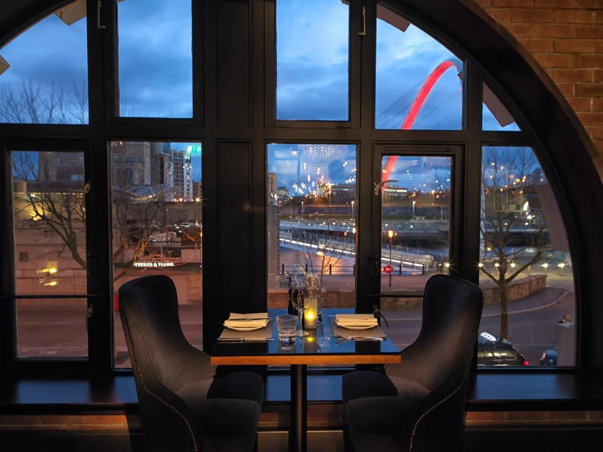 A table with chairs in front of a window at Malmaison Newcastle in Newcastle upon Tyne