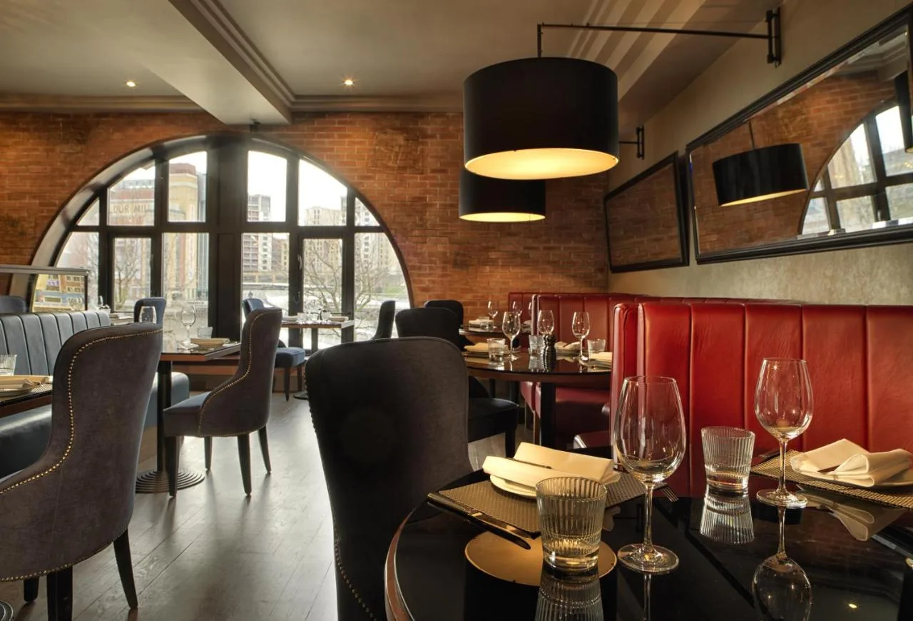 A restaurant with tables and chairs and a large window at Malmaison Newcastle in Newcastle upon Tyne
